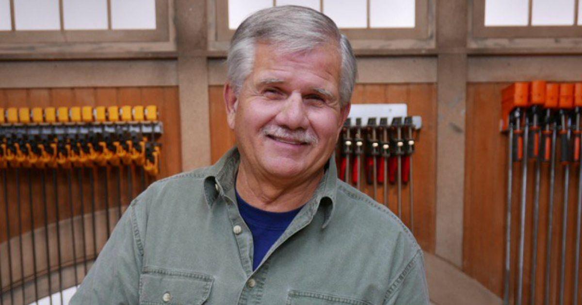 Tom Silva smiles in front of a wall of tools