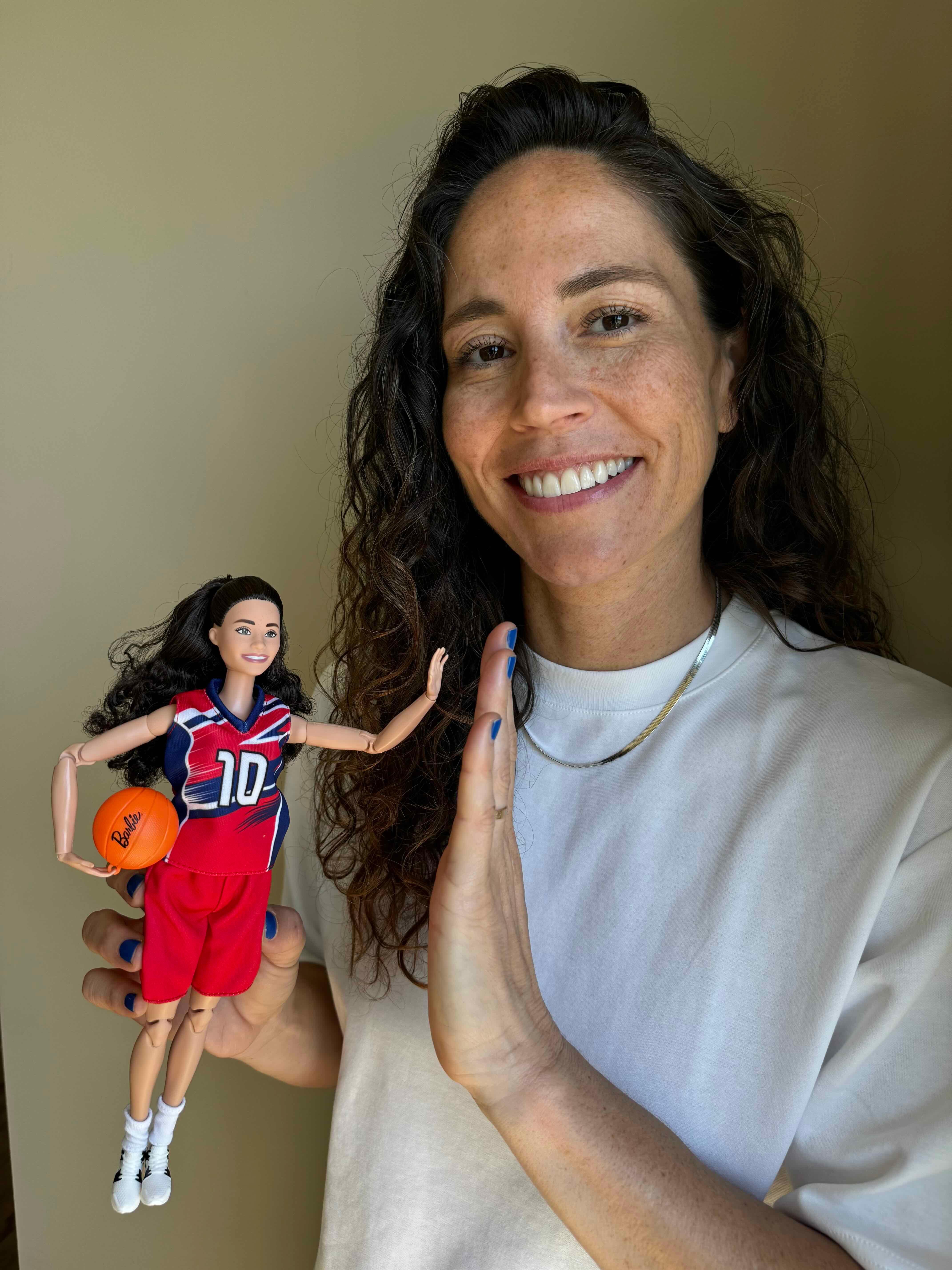 Sue Bird goes to high-five her Barbie role model doll.