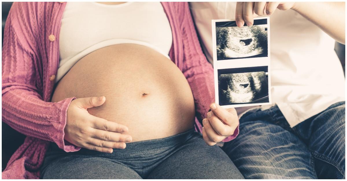 A pregnant woman holding her belly next to her partner.