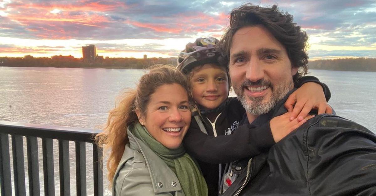 Sophie Trudeau, Haidrien Trudeau, and Justin Trudeau smile in front of a sunset and a lake.