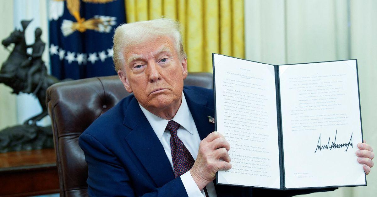 Donald Trump holding up a signed executive order.