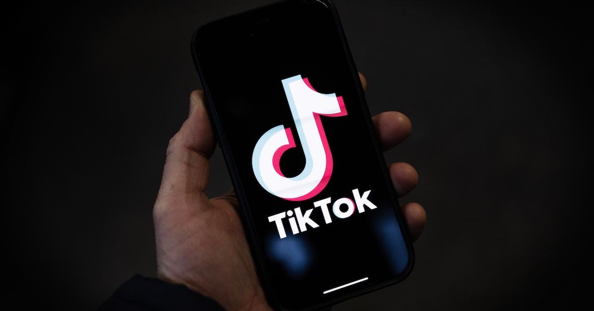 A person holding a smartphone displaying TikTok's logo