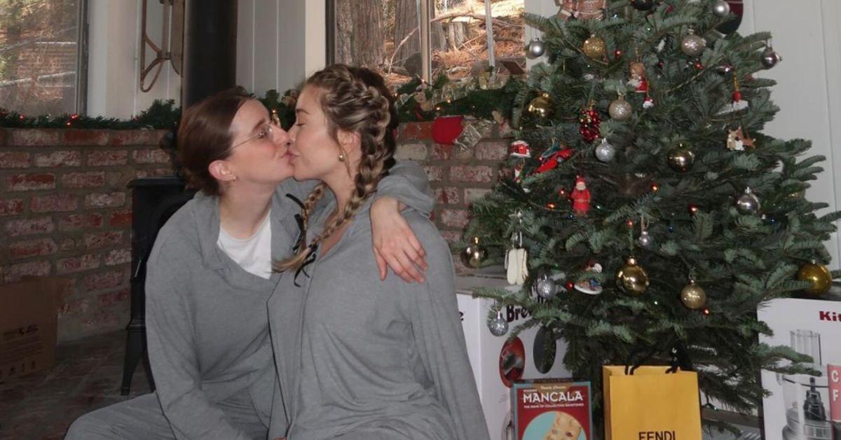 Robby Hoffman and Gabby Windey share a kiss in front of a Christmas tree.