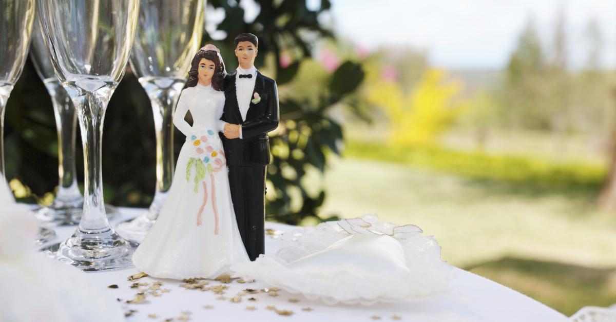 Bride and groom figurine on table by champagne flutes.