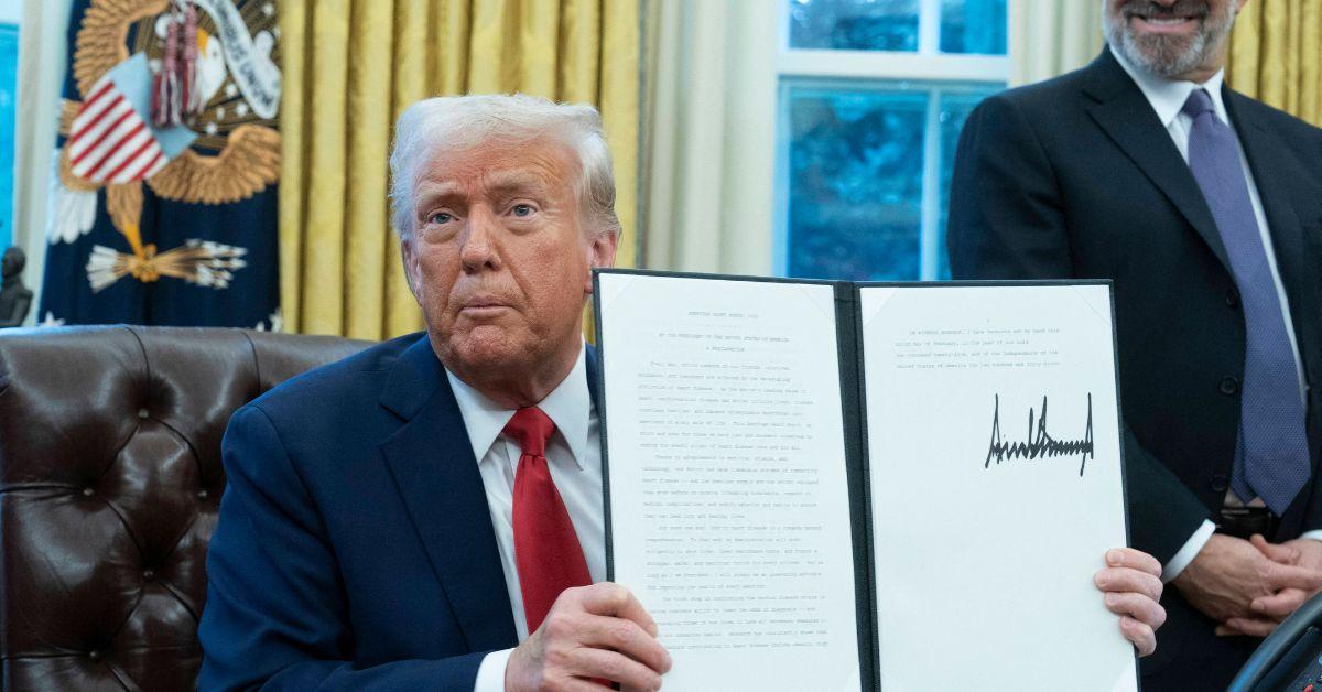 Donald Trump holds up a signed executive order. 