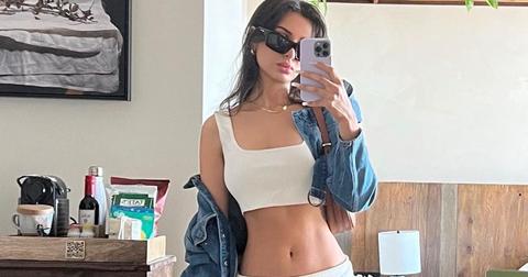 SSSniperWolf taking a selfie wearing a two piece white set with a denim jacket and black sunglasses.