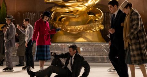 Miriam Maisel (Rachel Brosnahan) in a red coat, looks down on Gordon Ford (Reid Scott) in a business suit on the ice