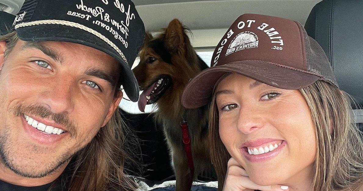 Noah and Abigail wear trucker hats and smile in the car with their dog