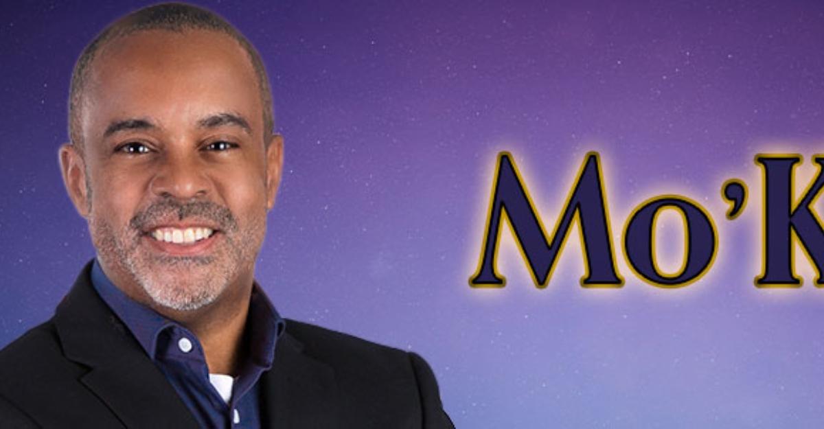 Mo'Kelly poses in front of his show's banner