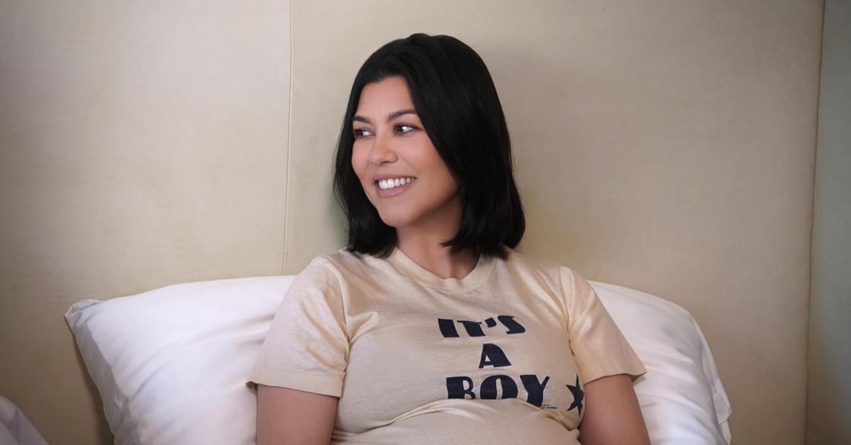 Kourtney Kardashian-Barker lays in bed with a shirt that says "it's a boy"