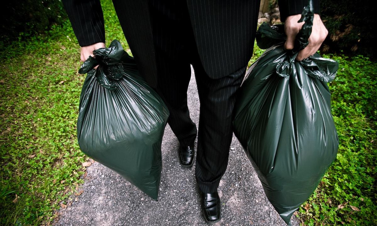 A person holding two trash bags