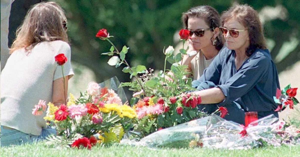 Nicole Brown Simpson's mother Juditha (R), and sisters Denise (C) and Tanya (L) sit next to her grave surrounded by flowers