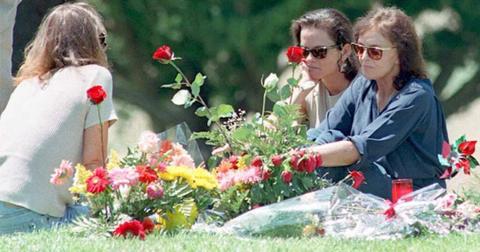 Nicole Brown Simpson's mother Juditha (R), and sisters Denise (C) and Tanya (L) sit next to her grave surrounded by flowers