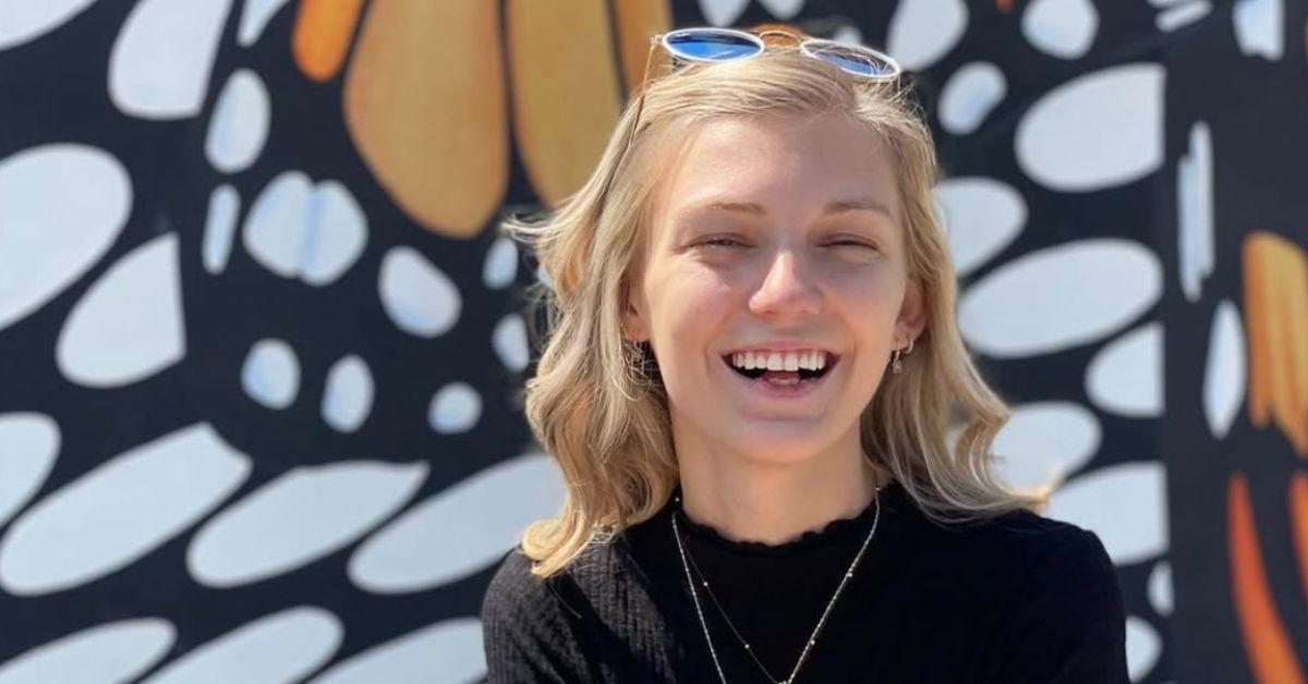 Gabby Petito smiling in front of a butterfly wall. 