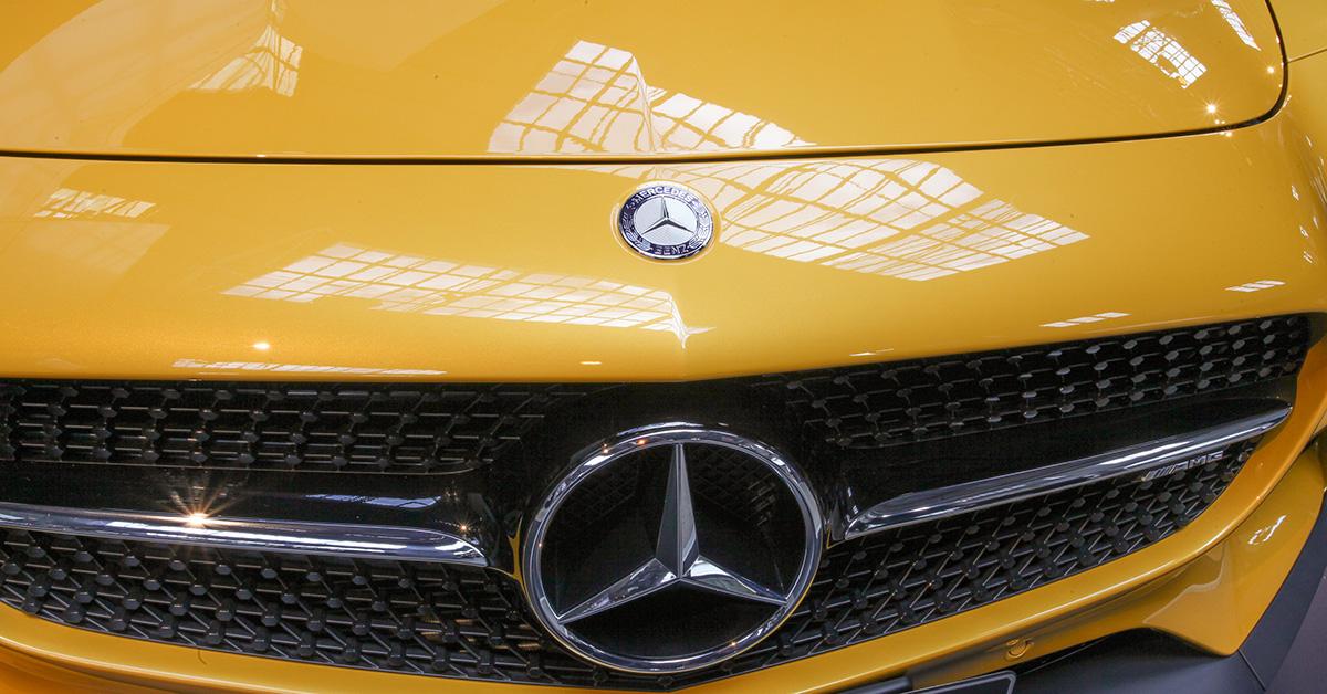 A close up on the grill of a yellow Mercedes-Benz.