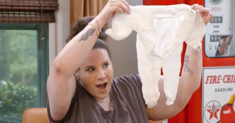 Whitney Thore holding up baby clothes.