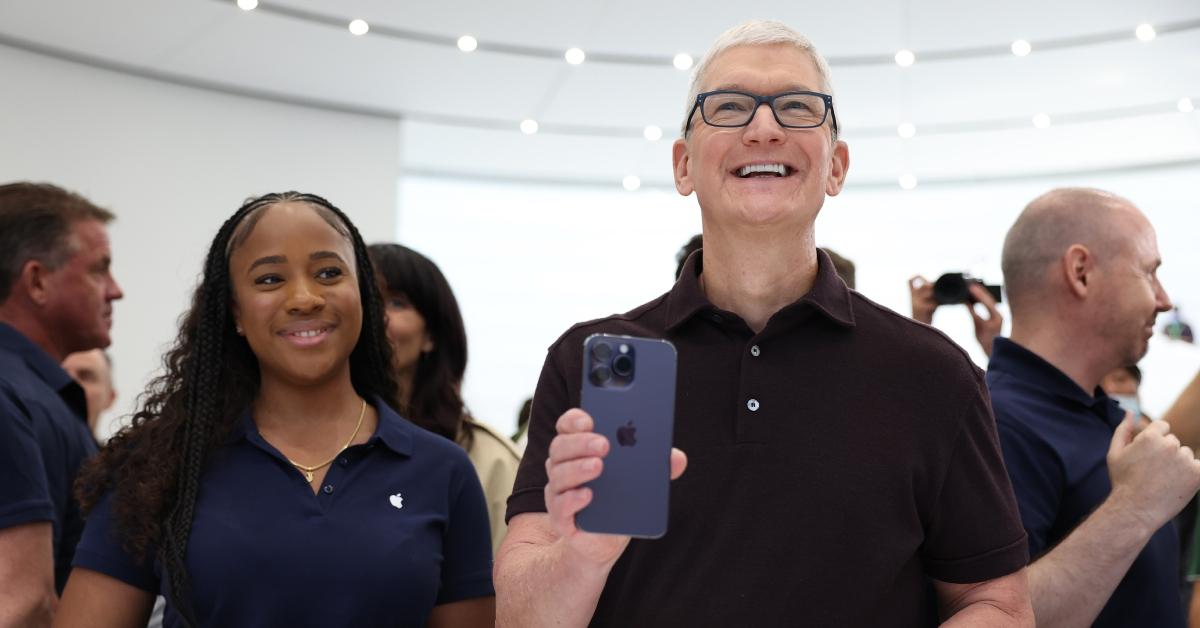 tim cook holding an iphone next to an apple employee