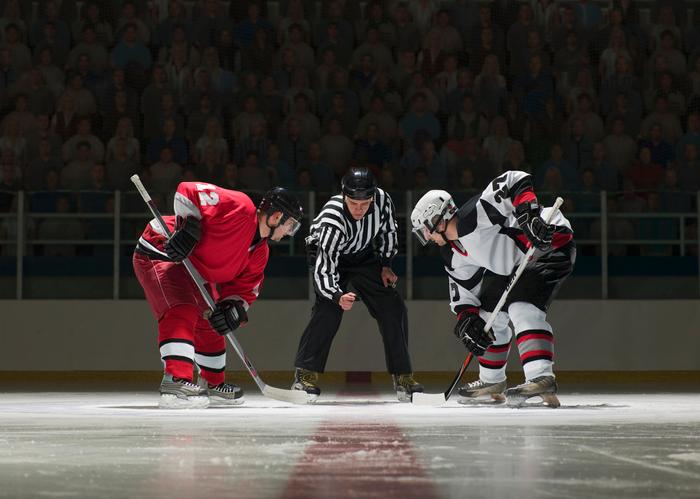 Two hockey players seen facing off during a puck drop