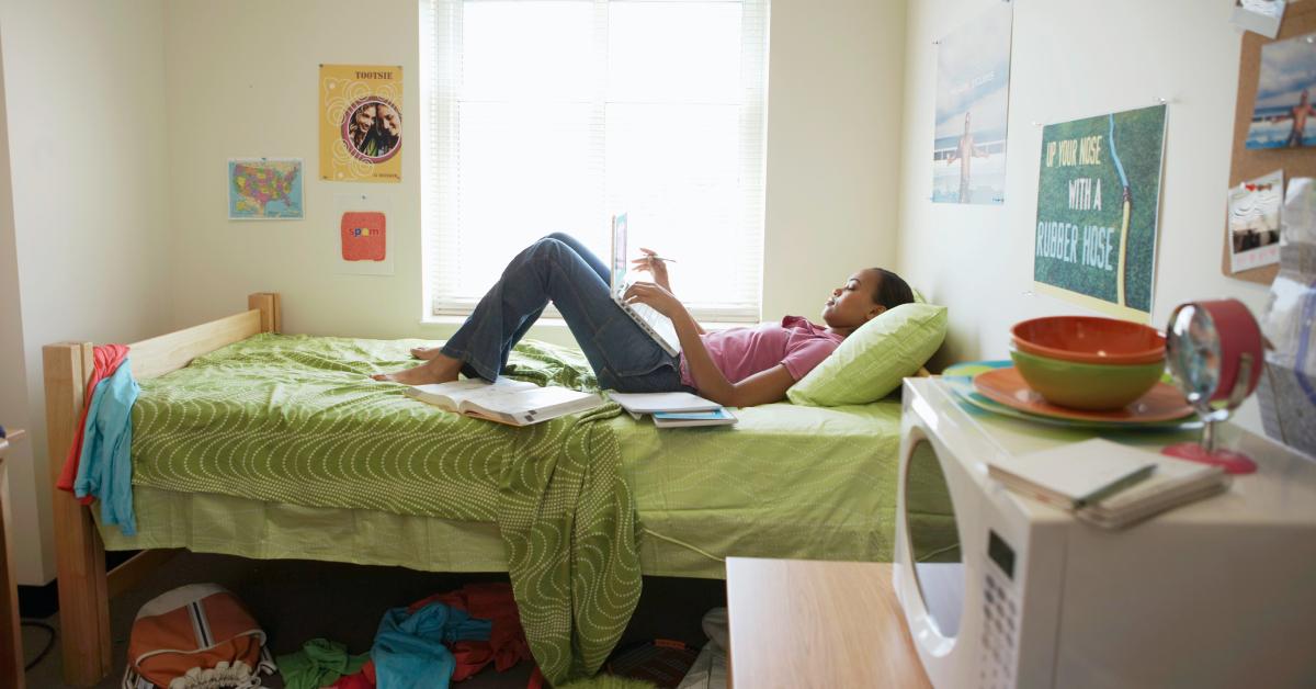 A female college students does schoolwork in her dorm room.