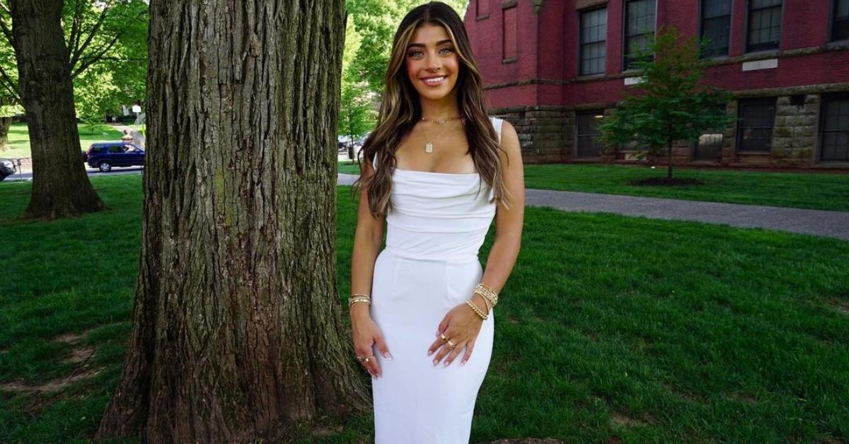 Gia Giudice stands by a tree in a white dress