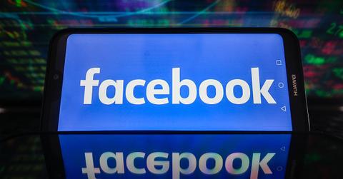 Facebook logo on a phone screen with a reflection below it.