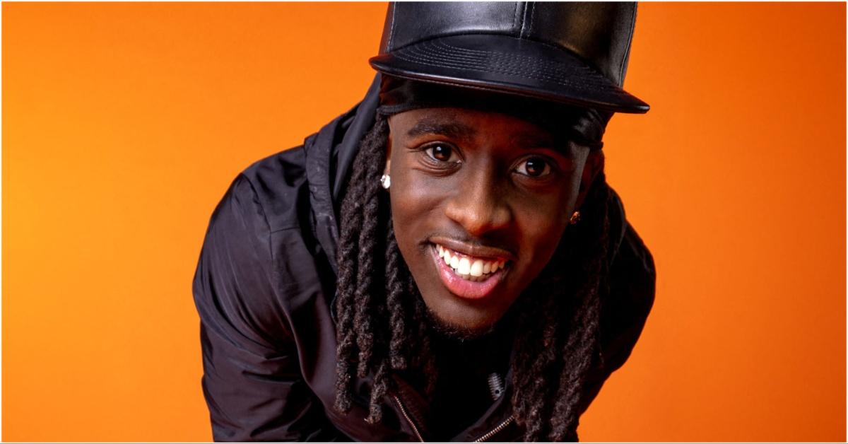 Kai Cenat smiling in front of an orange background