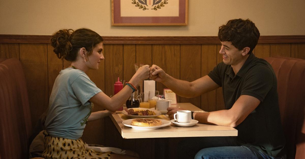Poppy and Alex sit in a booth at a diner in People We Meet on Vacation.