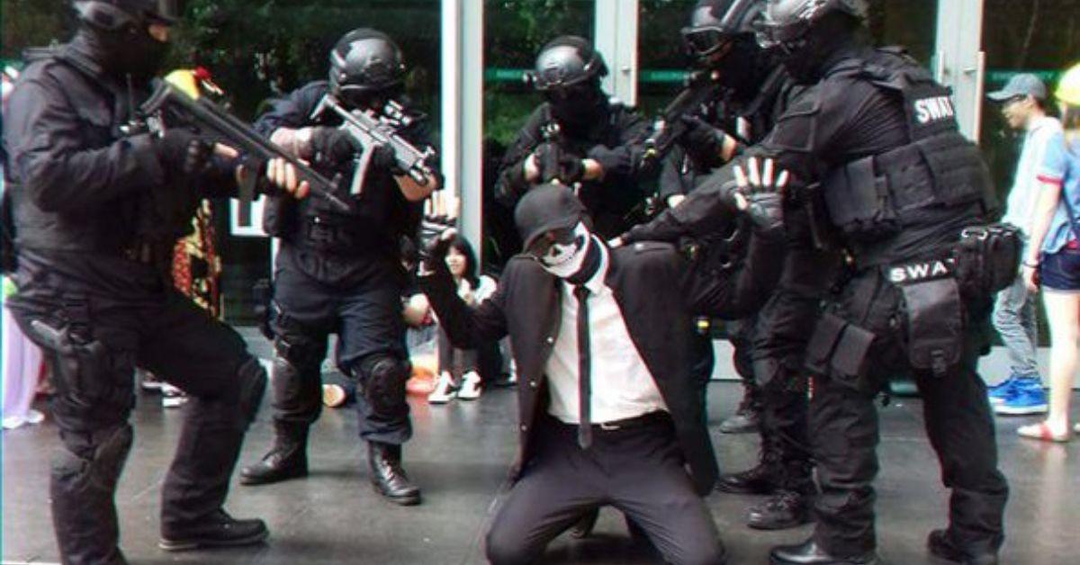 A Shadman cosplay on their knees surrounded by a SWAT team