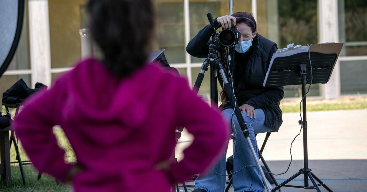 A photographer taking a picture of a child at school on picture day.