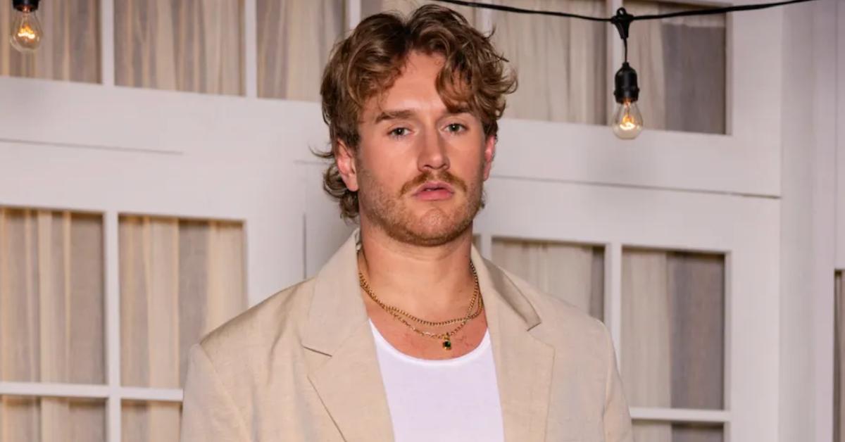 West Wilson wears an oversized beige suit over a classic white tank top with layered gold necklaces for the 'Summer House' Season 8 reunion.