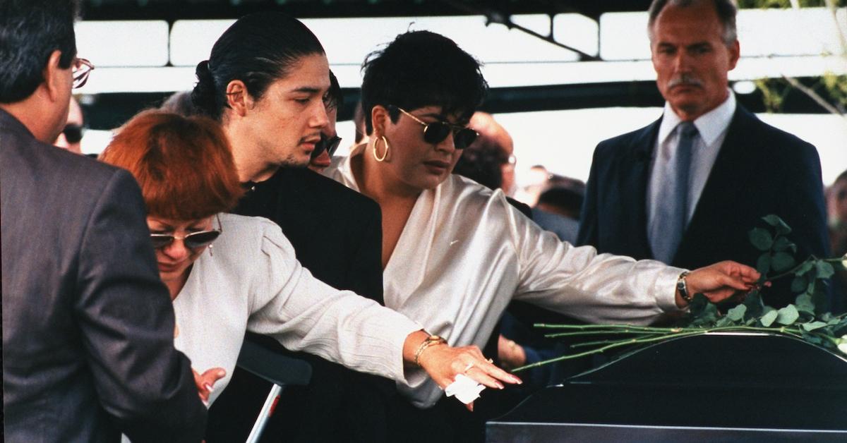 Selena's mother Marcela Quintanilla, husband Chris Perez, and sister Suzette laying roses atop casket at her funeral in 1995