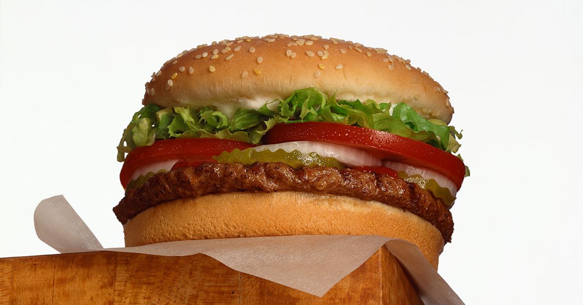 A burger sitting on the edge of a table. 