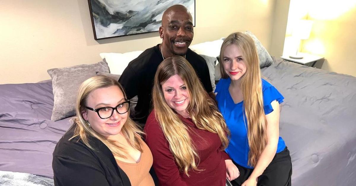 Davis family from 'Seeking Sister Wife' poses for a selfie while sitting on their bed.