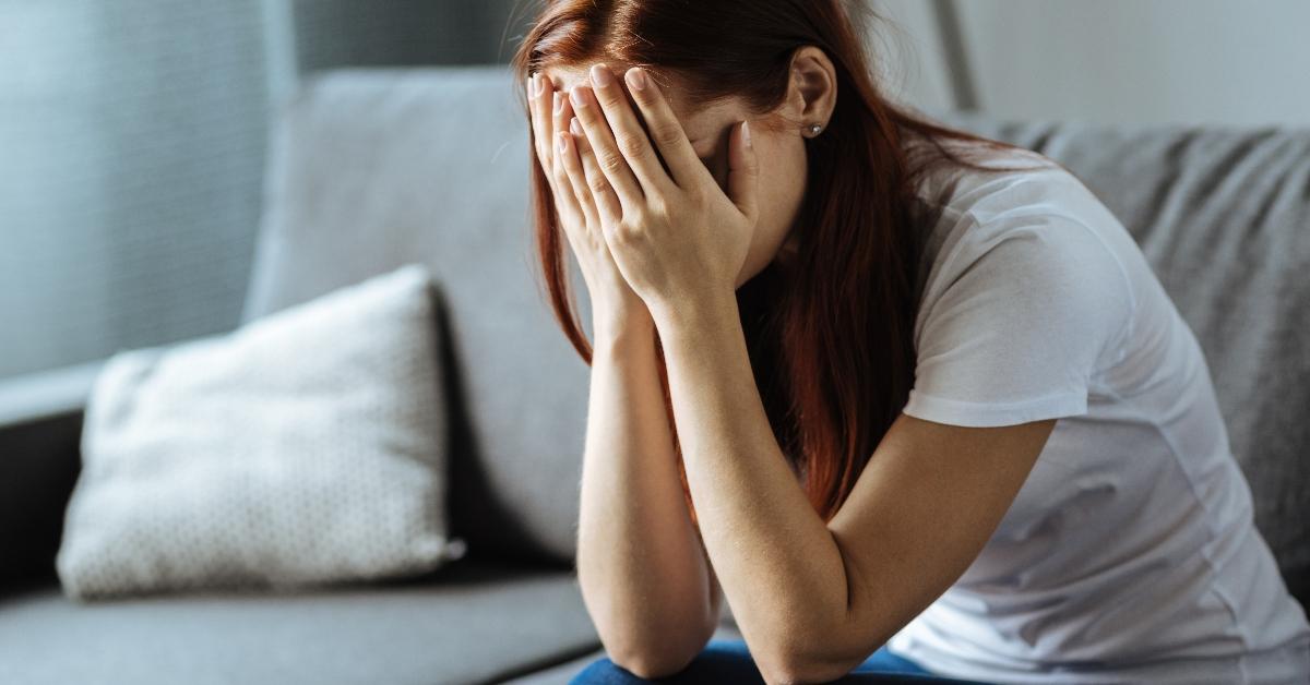 Unhappy young woman covering her face - stock photo