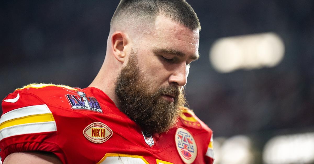 Travis Kelce wearing his football uniform looking down at the ground.