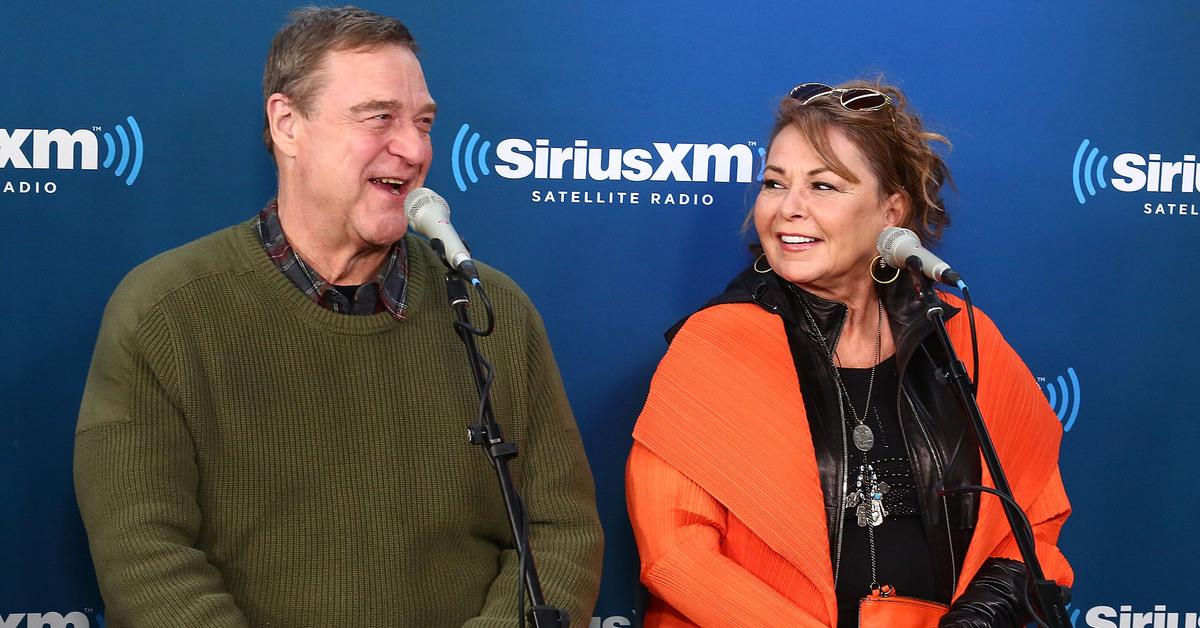 Roseanne Barr in orange sweater and John Goodman in green sweater doing a SiriusXM interview