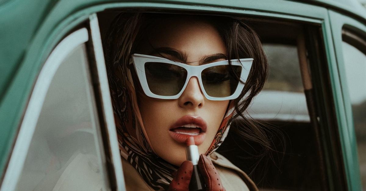 A woman applies lipstick in a car