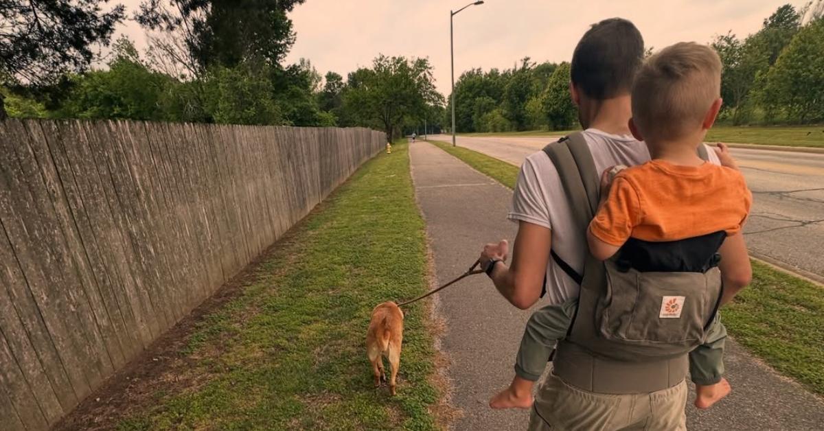 Derick Dillard walking with his youngest son on his back.