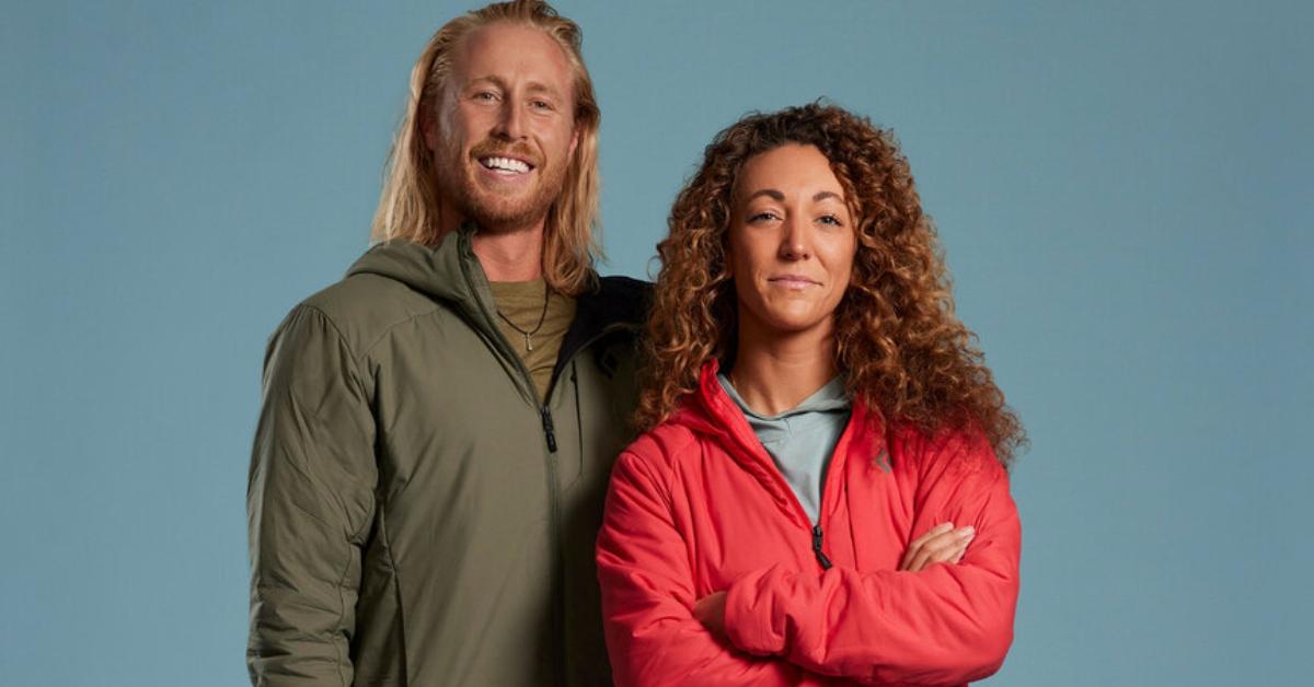 Creighton and Paulina stand in front of a blue background for Race to Survive: New Zealand