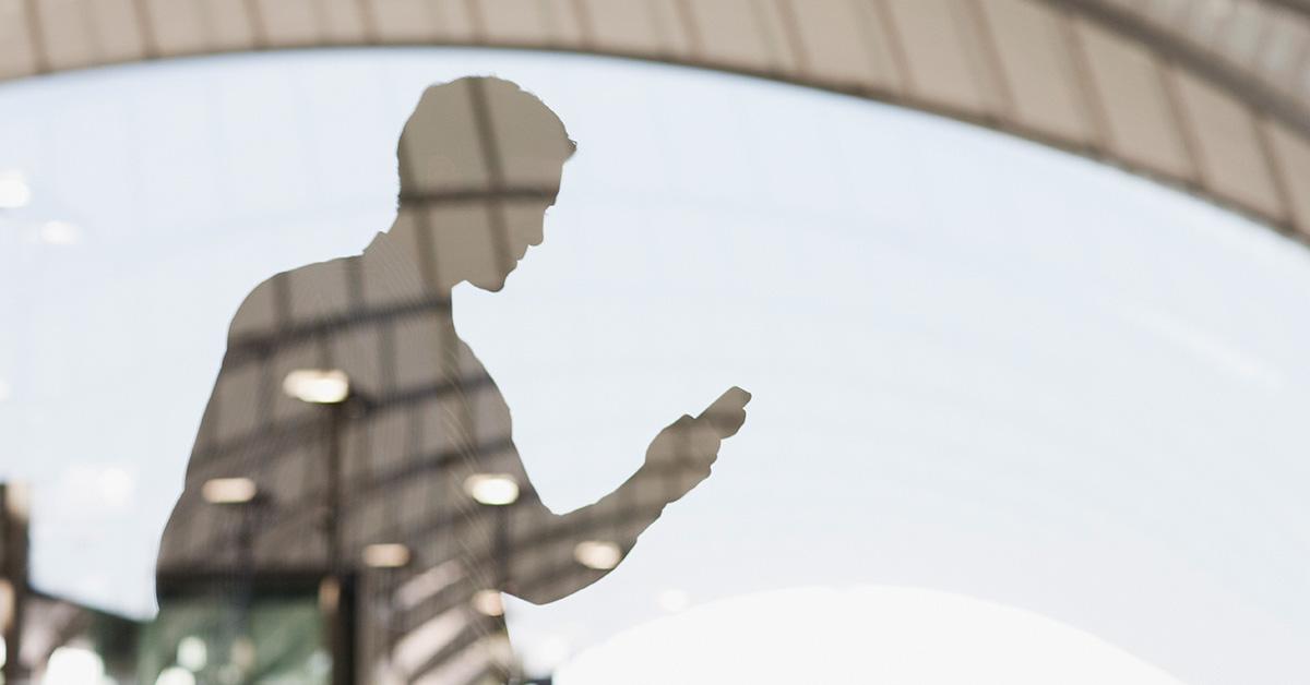 A shadow of a person on their cell phone. 