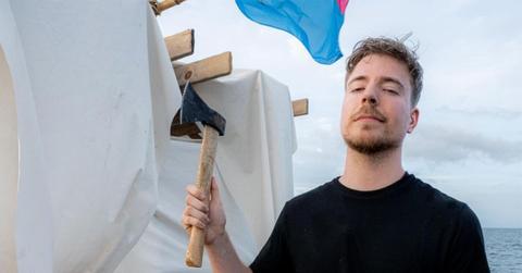 MrBeast holding an axe on a raft in the ocean.