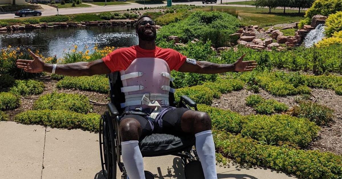 Patric Young with his arms outstretched in a wheelchair in a garden. 