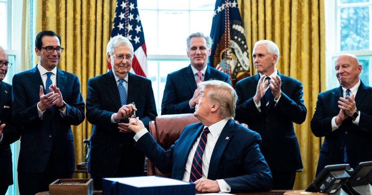 Donald Trump handing a pen to Mitch McConnell in the Oval Office. 