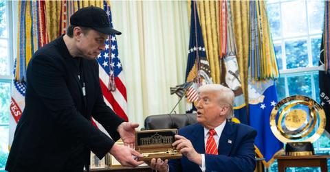 Elon Musk receiving a gift in the Oval Office.