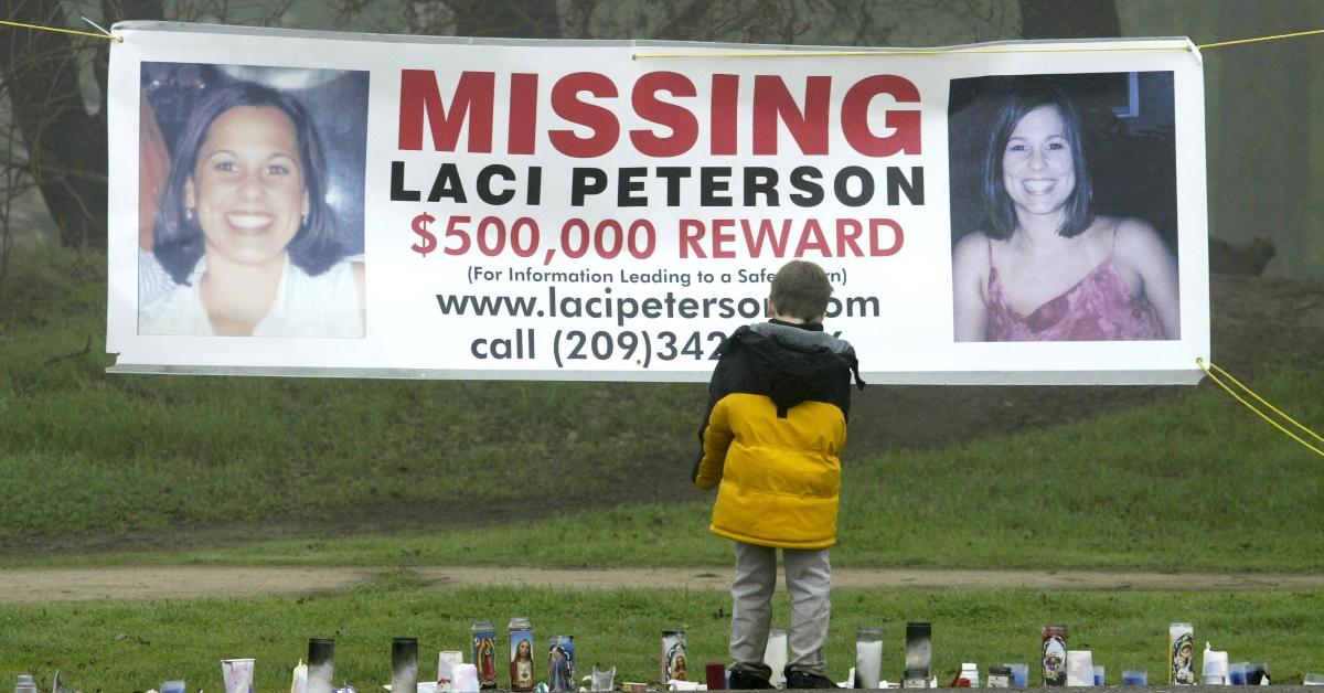 A child stands in front of a Laci Peterson Missing sign at the place her body was found.