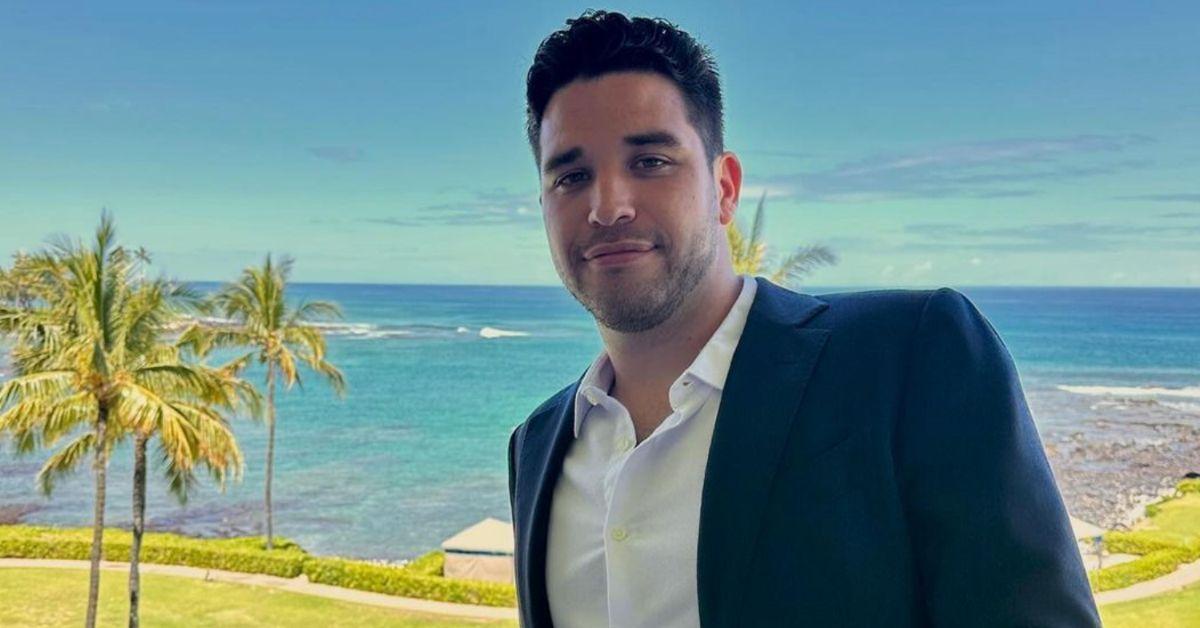 Devin Strader poses for a photo on a balcony in front of a beach