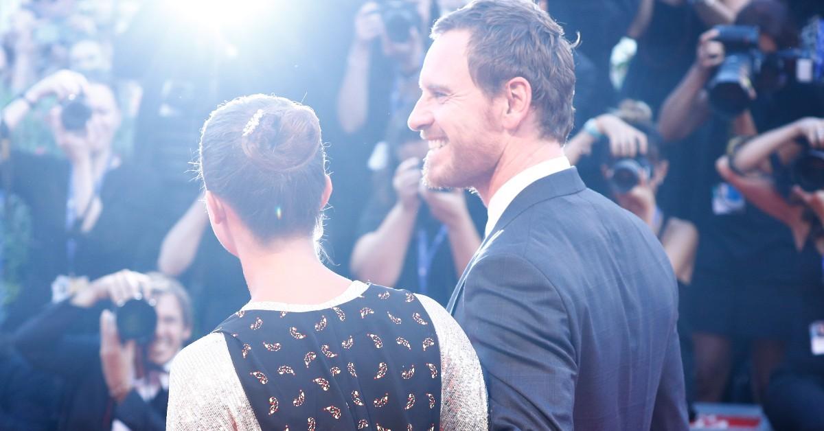 (L-R) Alicia Vikander, in a blue and white dress, and Michael Fassbender, in a suit, face photographers at the 73rd annual Venice Film Festival 