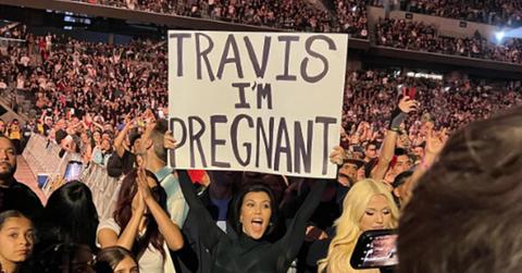 Kourtney Kardashian holding a sign revealing her pregnancy