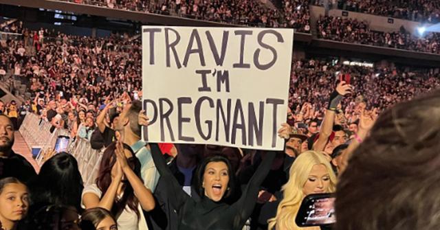 Kourtney Kardashian holding a sign revealing her pregnancy