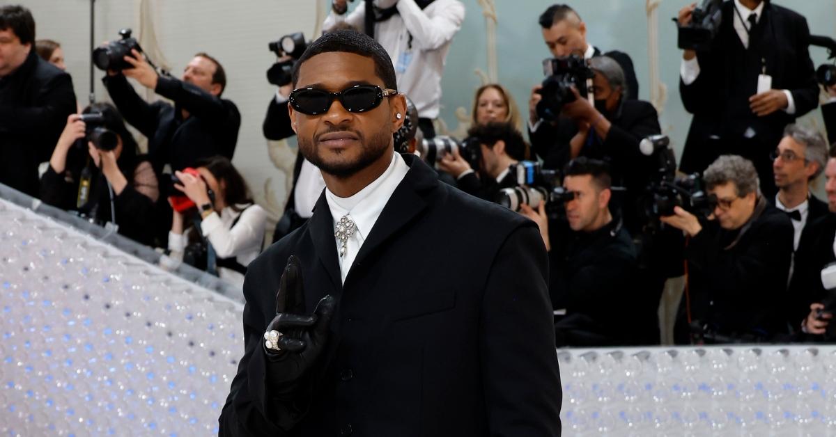 Usher wears black suit, tie, and sunglasses on Met Gala red carpet.